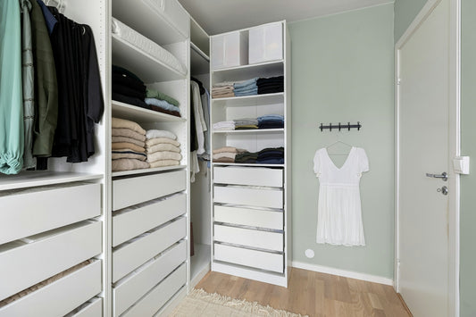 A walk in closet filled with lots of white drawers