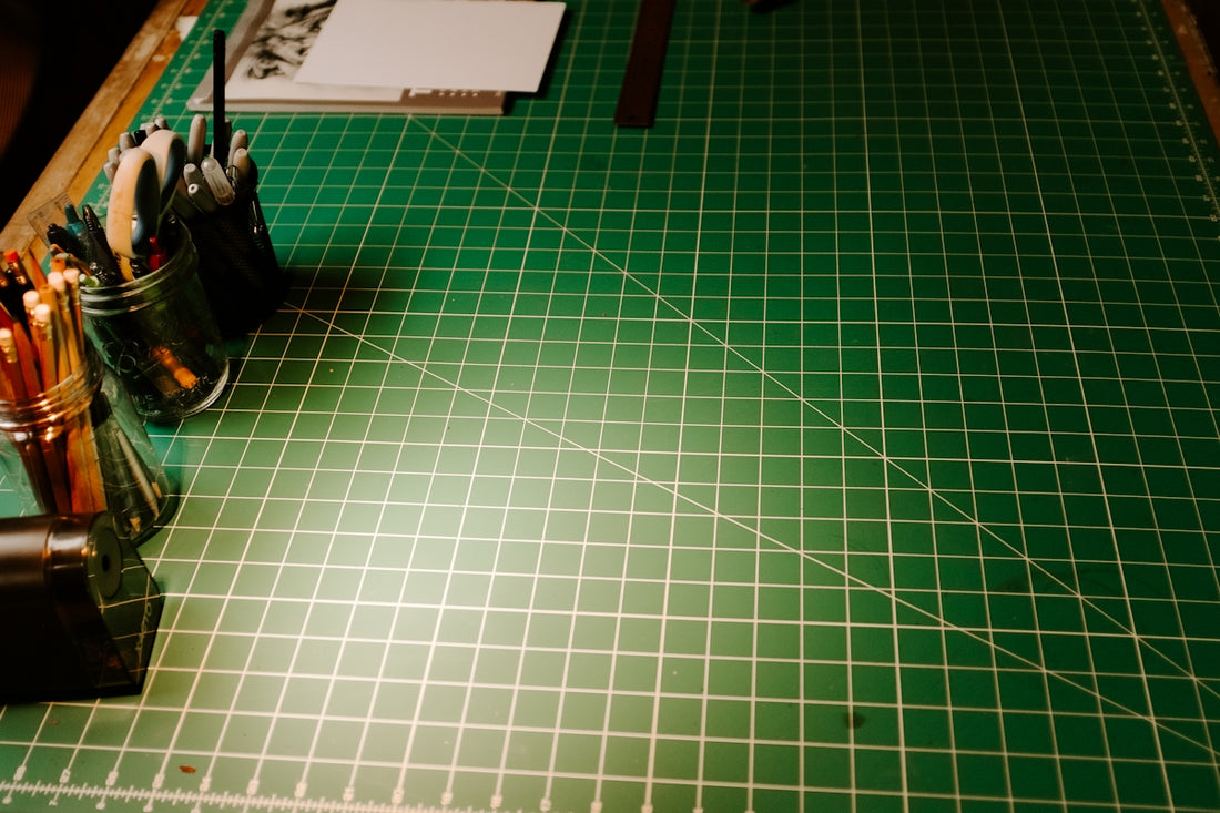 A green cutting mat with a knife and a pair of scissors