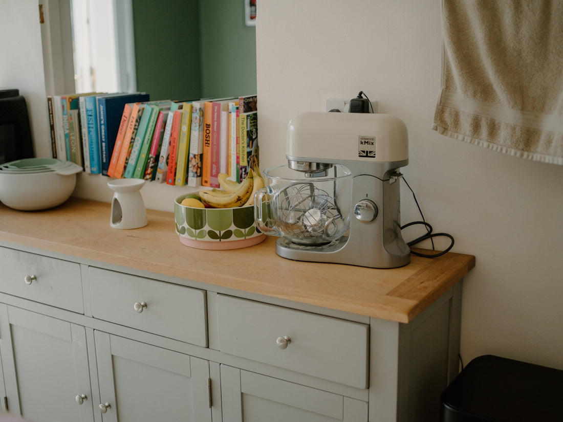 Kitchen counter with mixer, fruit bowl, and books.