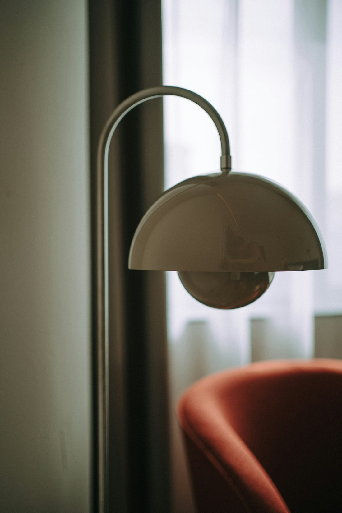 A modern floor lamp beside an orange armchair