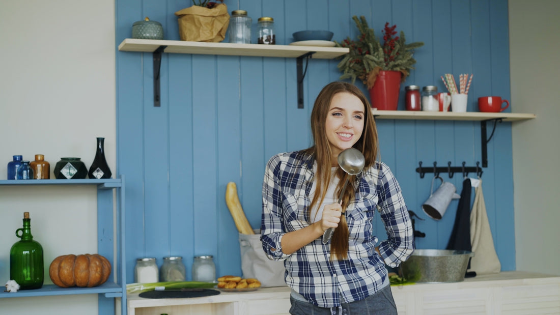 Woman singing into a ladle in a kitchen.