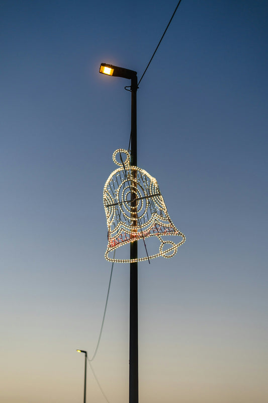 A decorative bell light hangs from a lamppost at dusk.