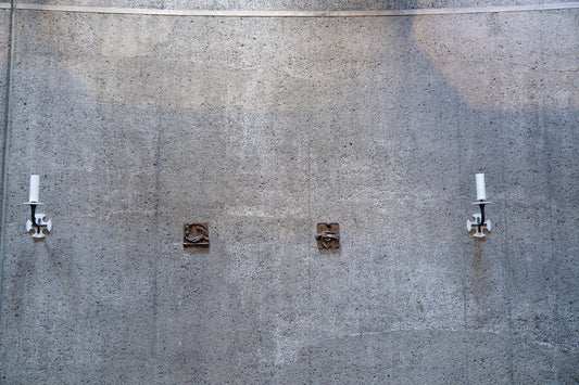 Two white antennas mounted on a concrete wall