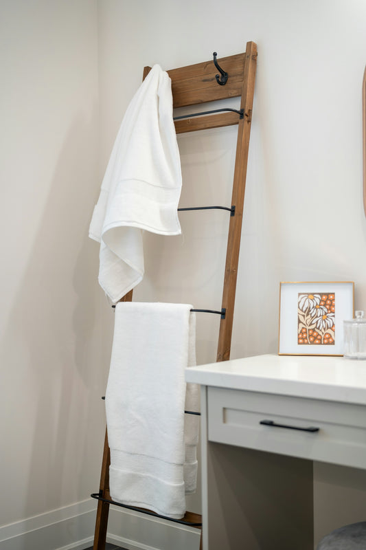 Wooden ladder rack with white towels in a bathroom.