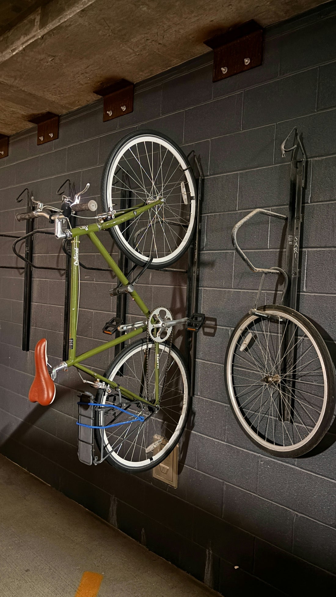 Green bicycle hanging on a brick wall