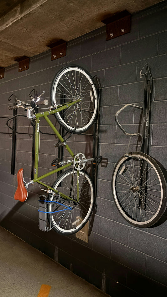 Green bicycle hanging on a brick wall