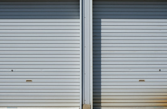 Two closed metal roll-up garage doors side by side