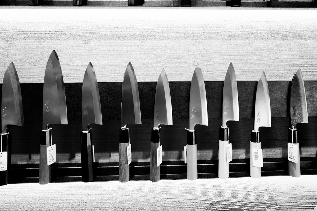 A row of sharp kitchen knives displayed on a rack.