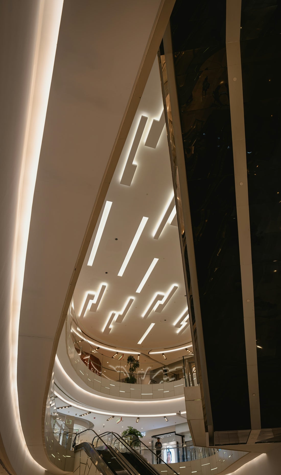 Modern multi-level interior with escalators and linear lighting