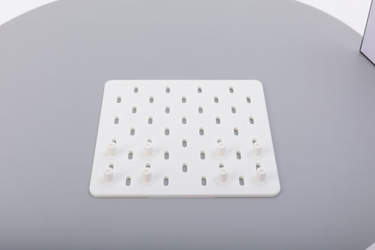 A white pegboard with some pegs on a gray surface.