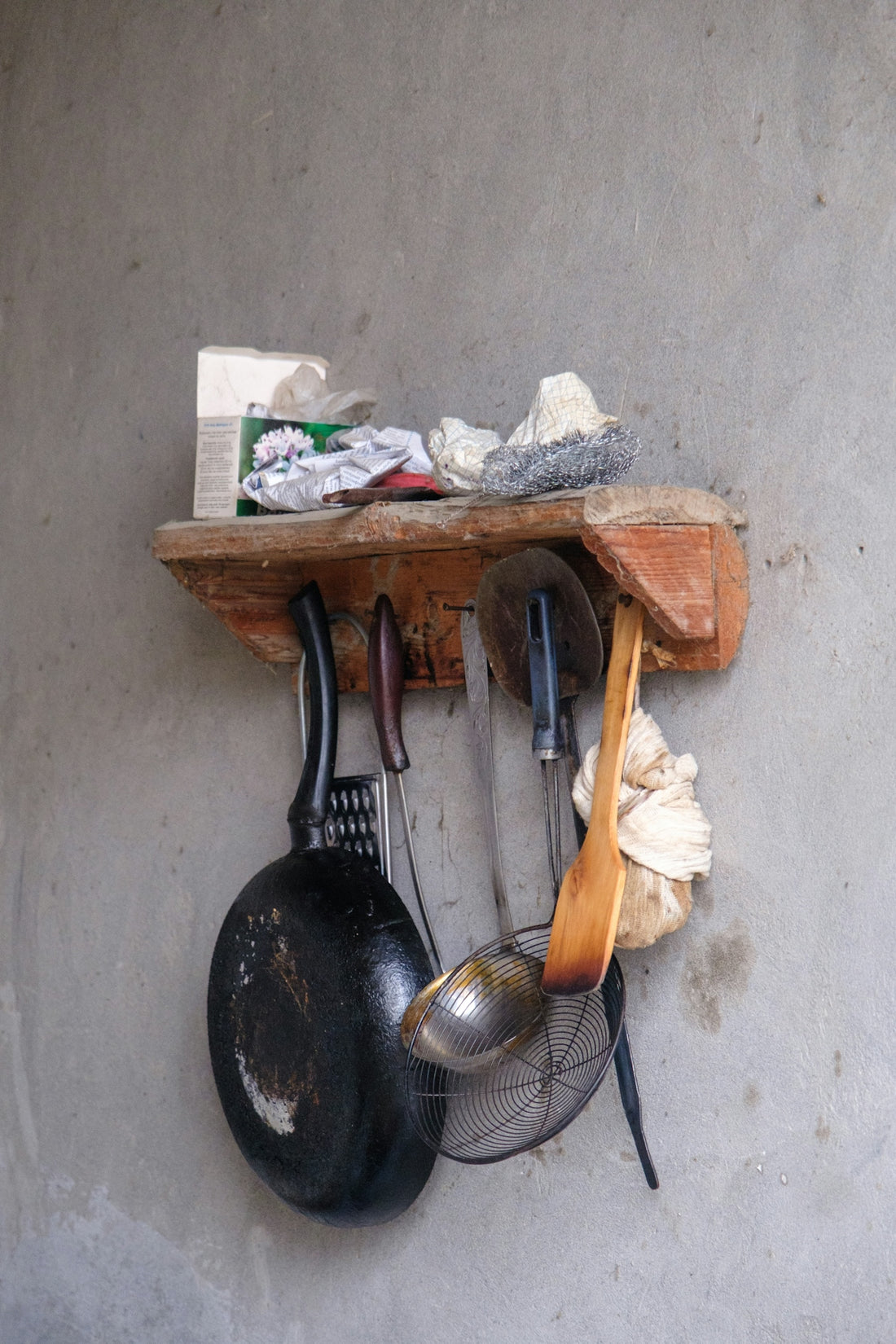 Various kitchen tools hanging from a rustic wooden shelf