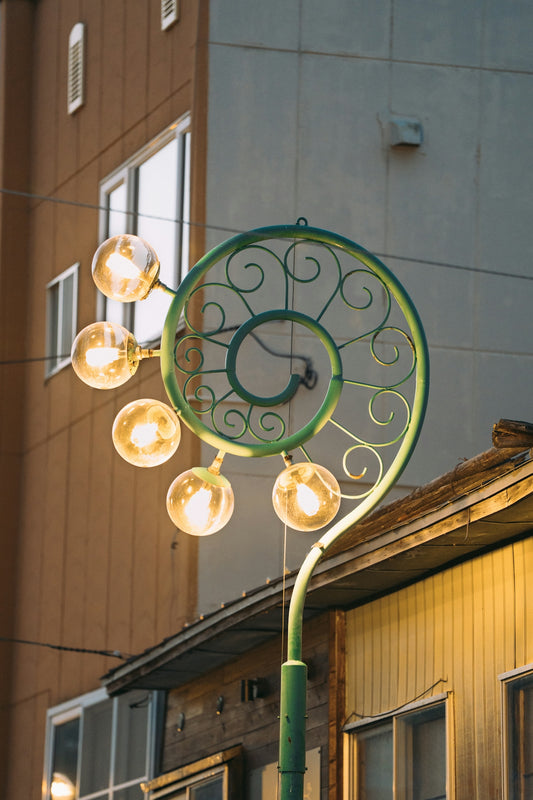 A decorative green spiral street lamp with glowing globes.