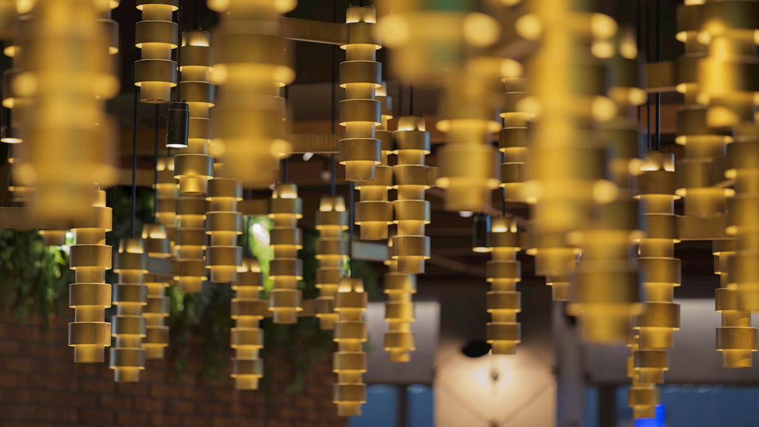 Golden cylindrical hanging decorations illuminate a modern interior.